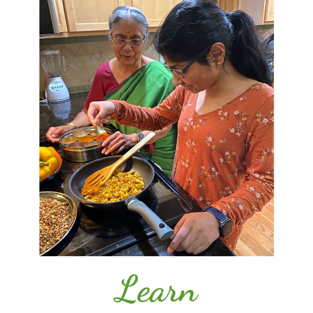 Picture of a Grand Daughter learning to cook from her Grandma how to cook Indian food using Indian spice box.  The spice box contains commonly used spices in Indian cooking like Turmeric, Cayenne, Coriander seed powder, Cumin and more spices