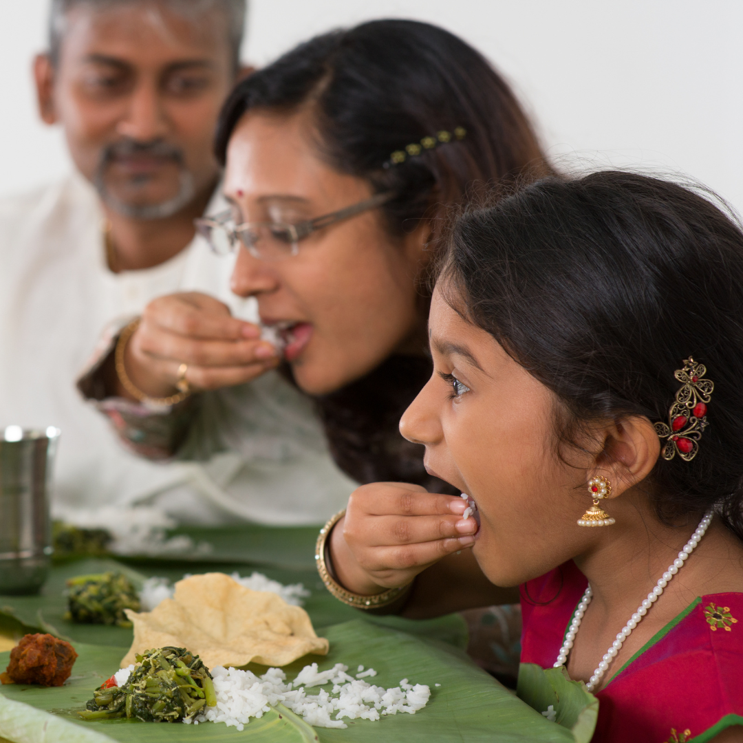 Picture of a family enjoying Indian Food served on a plantain leaf. .